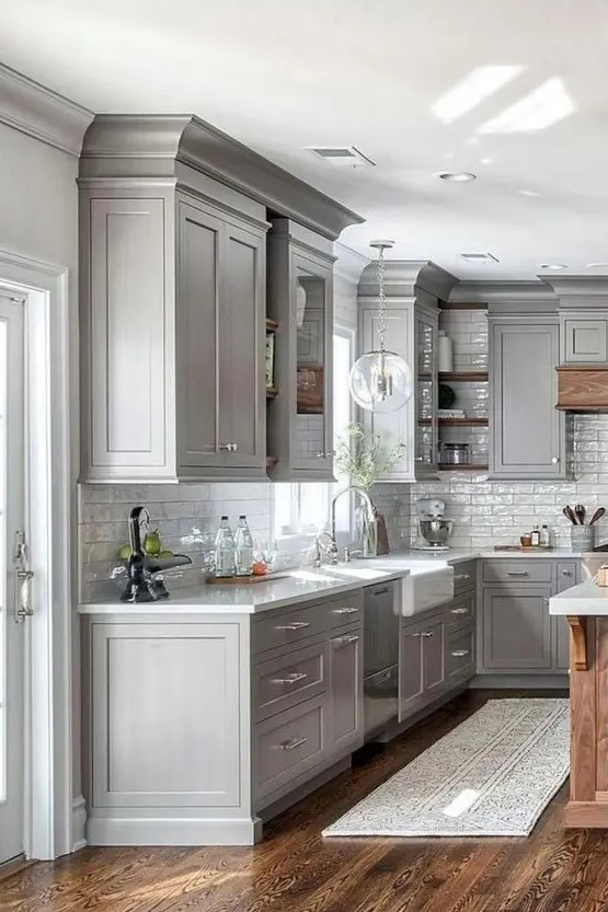 a modern farmhouse grey kitchen with white stone countertops and a white subway tile backsplash, with neutral fixtures is chic