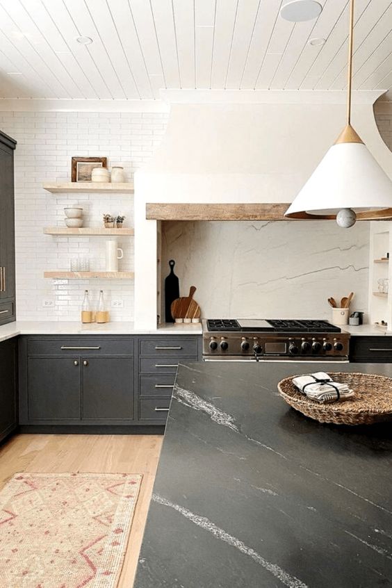 a modern farmhouse kitchen with soot cabinets, a large white hood, open shelves, a kitchen island with a stone countertop