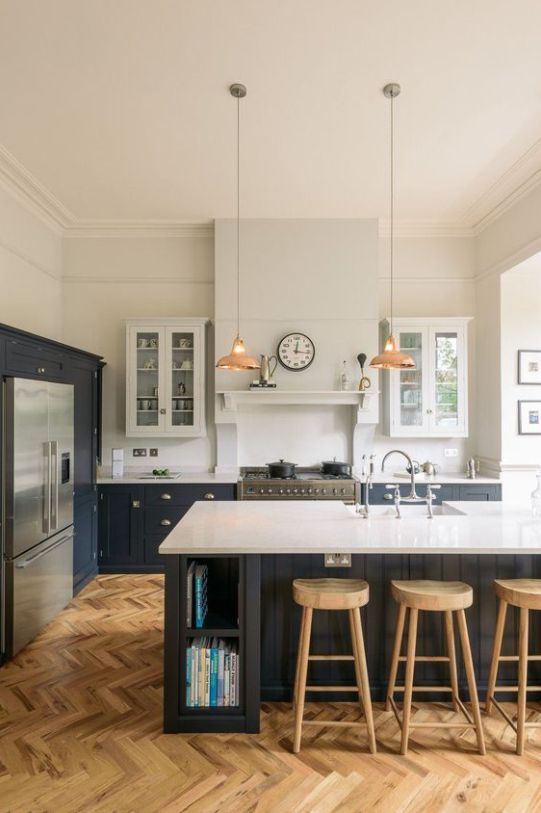 a modern farmhouse kitchen with white and graphite grey cabinets, white stone countertops, pendant lamps and wooden stools