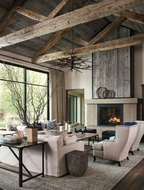 a modern farmhouse living room with reclaimed wood, a fireplace, neutral seating fruniture, coffee tables and an antler chandelier