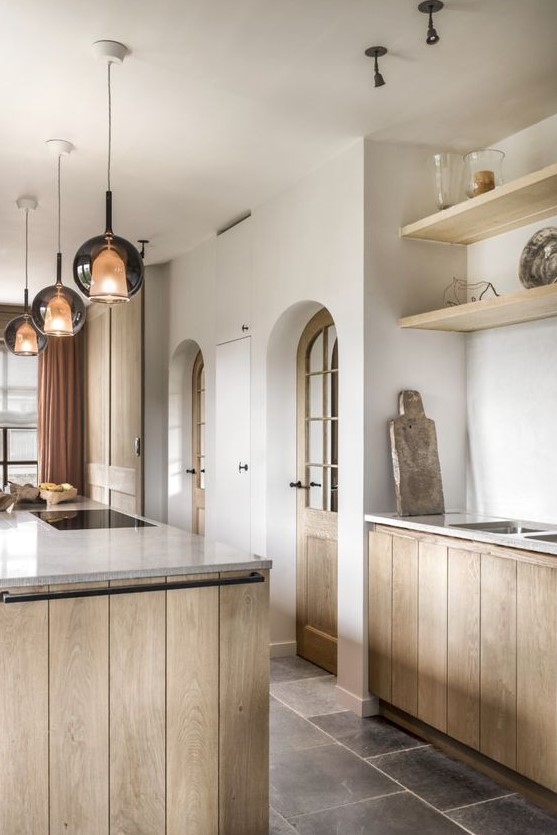 a modern rustic kitchen with stained planked cabinets, built-in shelves, pendant lamps and grey stone countertops