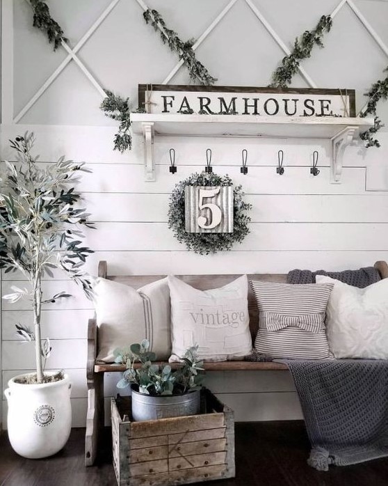 a neutral farmhouse entry with a sign, greenery, potted plants, a wooden bench with neutral textiles