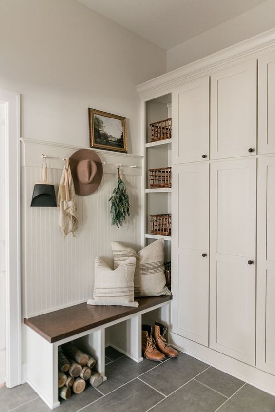 a neutral modern farmhouse entryway with a large storage unit, a built-in bench, some baskets and a rack