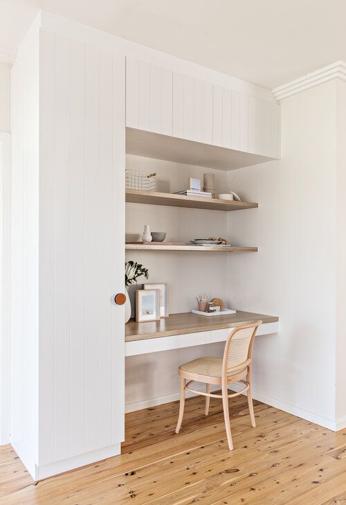 a niche with built-in shelves and a desk, a rattan chair, some decor and greenery, some books is a lovely nook