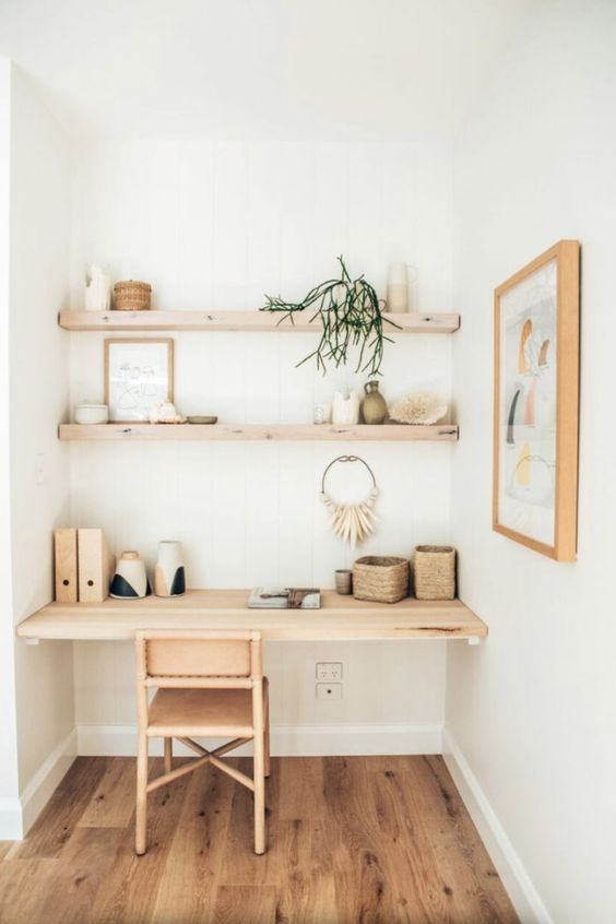 a niche with built-in shelves and a desk, some vases, books, baskets and boho decor, a rattan chair and an artwork