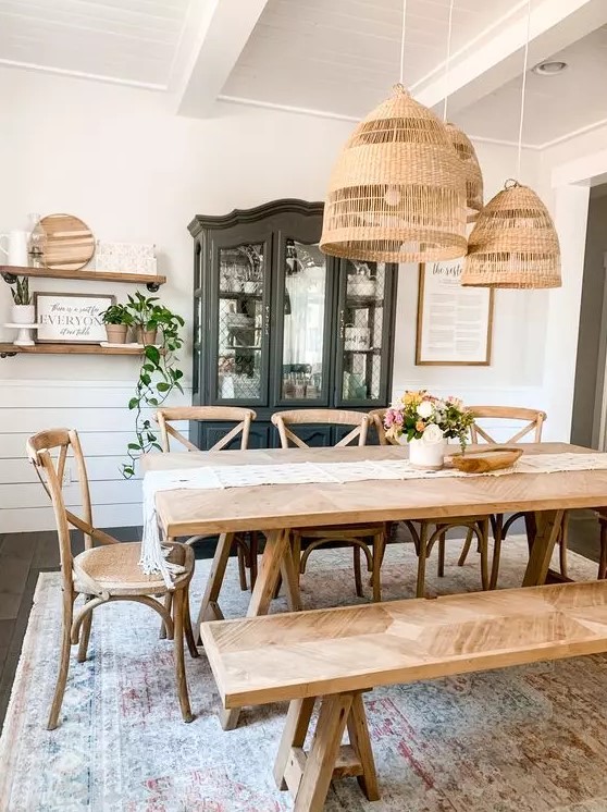 a rustic dining space with a black storage unit, a stained wooden table and a bench, lovely stained chairs and a cluster of pendant lamps