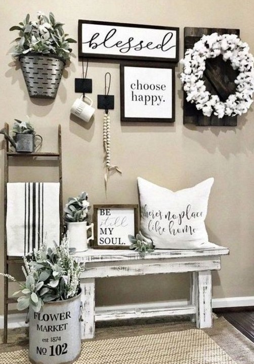 a simple farmhouse entry with a gallery wall, a cotton wreath, potted greenery and a pillow on the bench