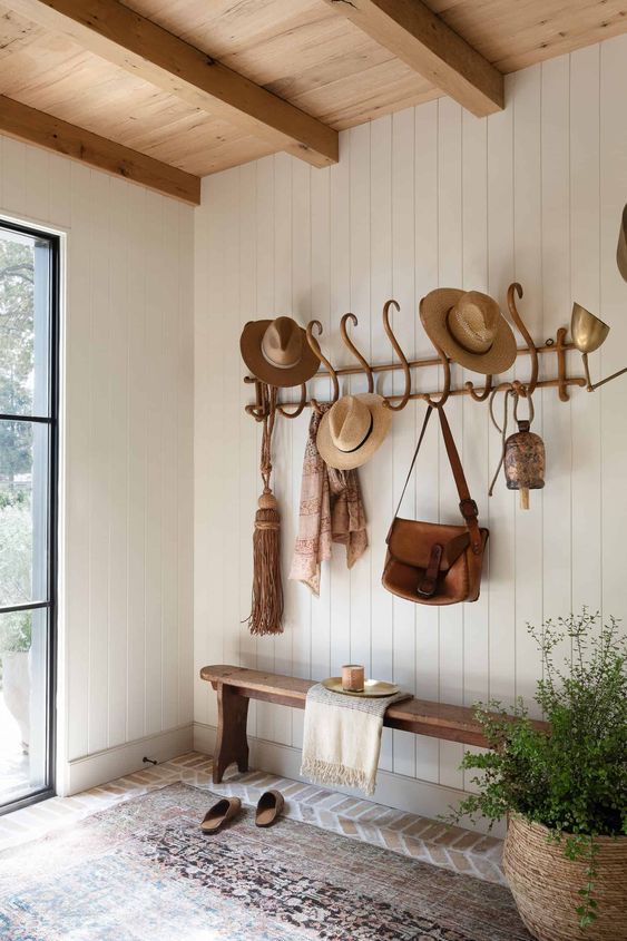 a simple modern farmhouse entryway with a shipalp wall, a stained bench and a rack, a potted plant and a rug