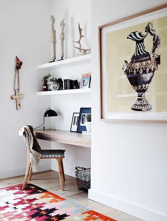 a small modern awkward nook with built-in shelves, a stained built-in desk, a woven chair, antlers, books and artworks and a basket