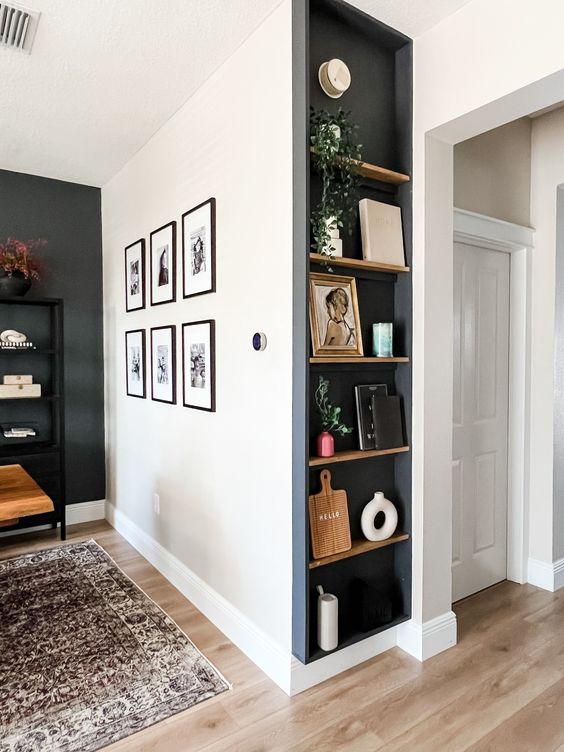 a stylish and contrasting space with a black accent wall, a gallery wlal, a niche done black with shelves that are used for decor