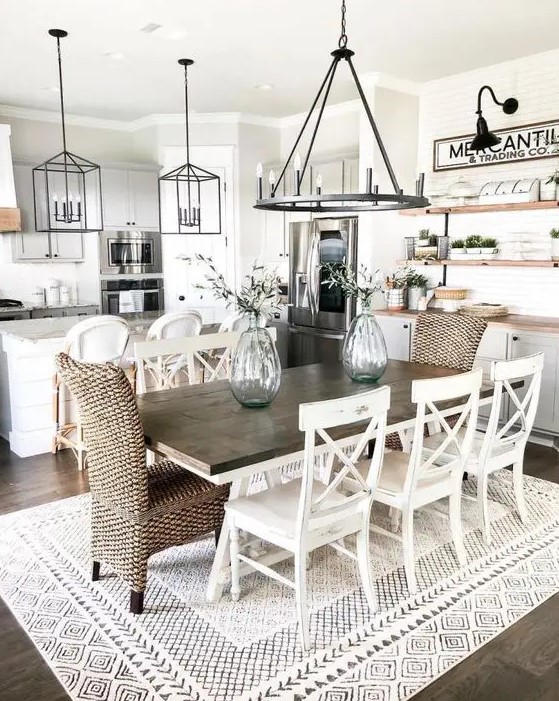 a stylish modern country dining space with a stained table, woven and wooden chairs, a metal chandelier and a buffet at the wall