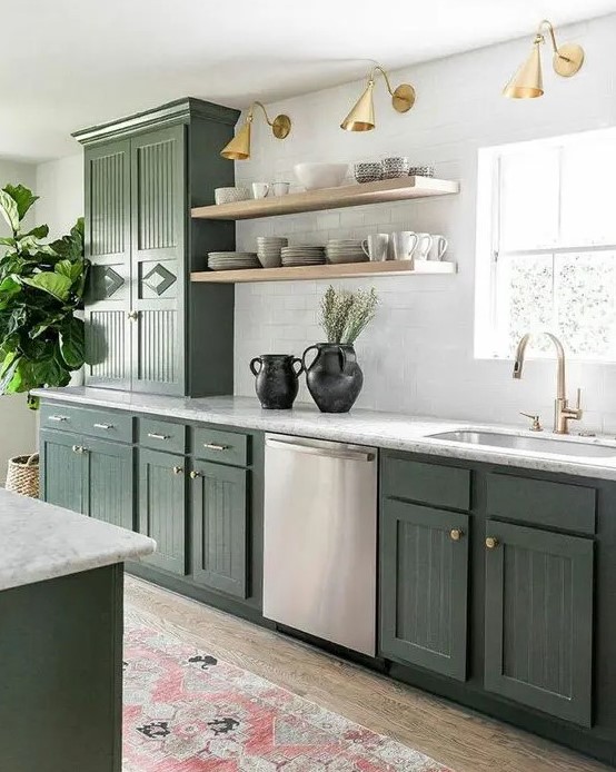 a stylish olive green farmhouse kitchen with fluted cabinets, white stone countertops, open shelves, brass and gold lamps