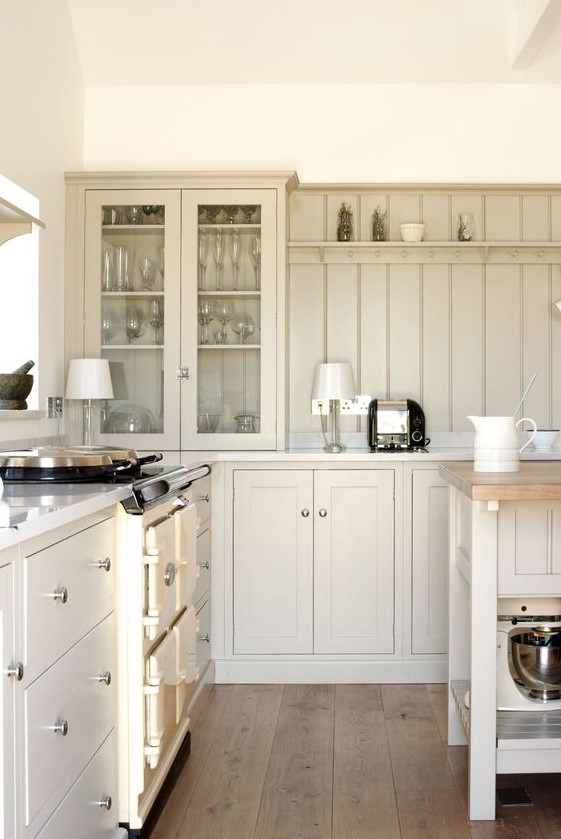 a tan kitchen with usual and glass cabinets, a matching beadboard backsplash and white countertops is a chic space