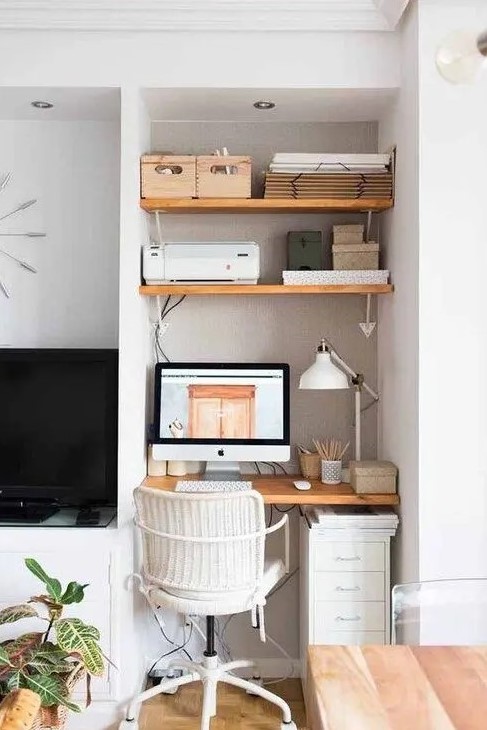 a tiny awkward nook space taken by a built-in working space - a desk, some shelves and a white office chair plus a white table lamp