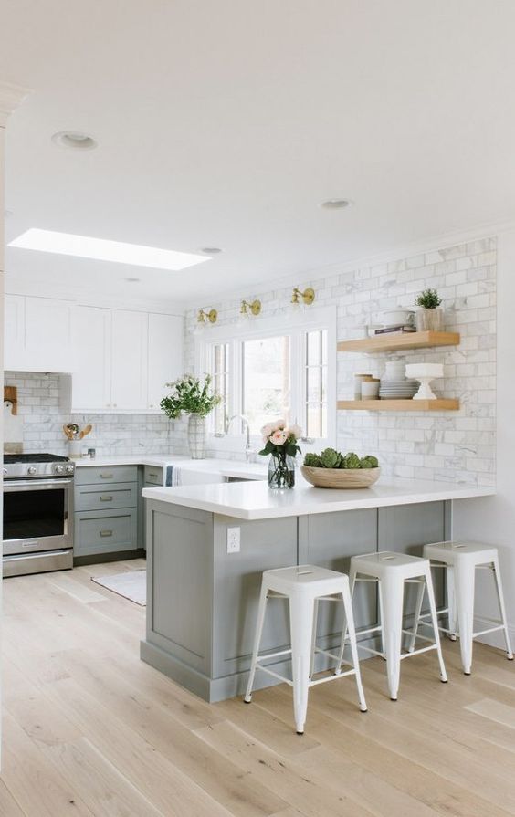 a two-tone modern farmhouse kitchen with white and grey cabinets, open shelves, white marble tiles and metal stools