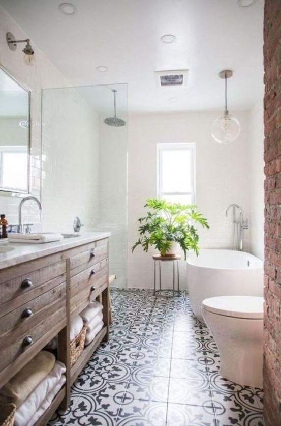 a welcoming farmhouse bathroom with a stained vanity, a brick wall, a mosaic tile floor and an oval tub