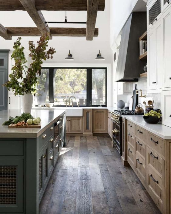 a welcoming modern farmhouse kitchen with stained and white cabinets, a grey kitchen island and a hood, wooden beams