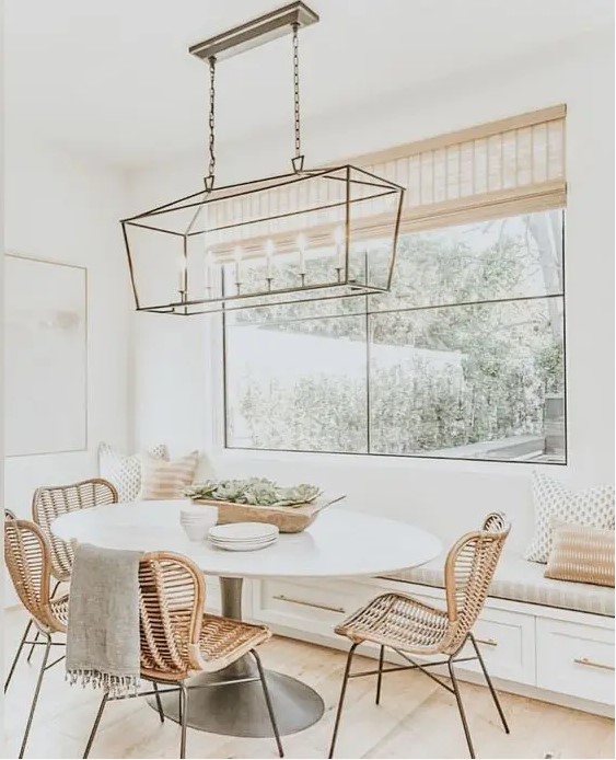 a welcoming modern farmhouse neutral dining space with a built-in bench, an oval table, rattan chairs, a chic brass pendant lamp