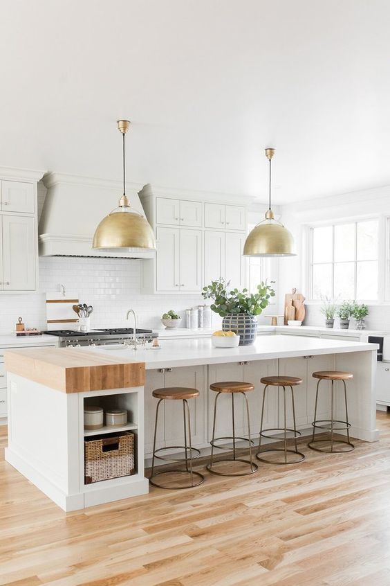 a white modern farmhouse kitchen with shaker cabinets, a large kitchen island with storage space, a white tile backsplash and pendant lamps