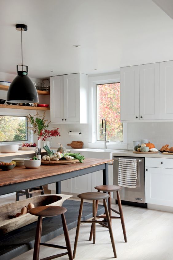 a white modern farmhouse kitchen with shaker cabinets, a soot table and kitchen island, pendant lamps and wooden stools