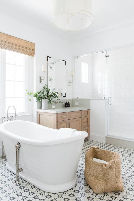 an airy modern farmhouse bathroom with a shower space, an oval tub, a basket, with a timber vanity and shades plus greenery