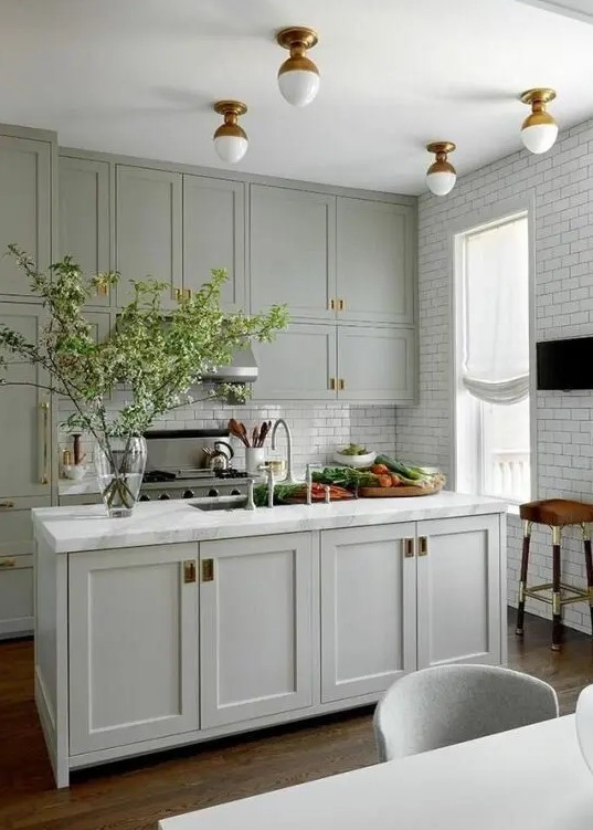 an amazing pale green modern country kitchen with shaker cabients, white subway tiles, brass touches for extra elegance