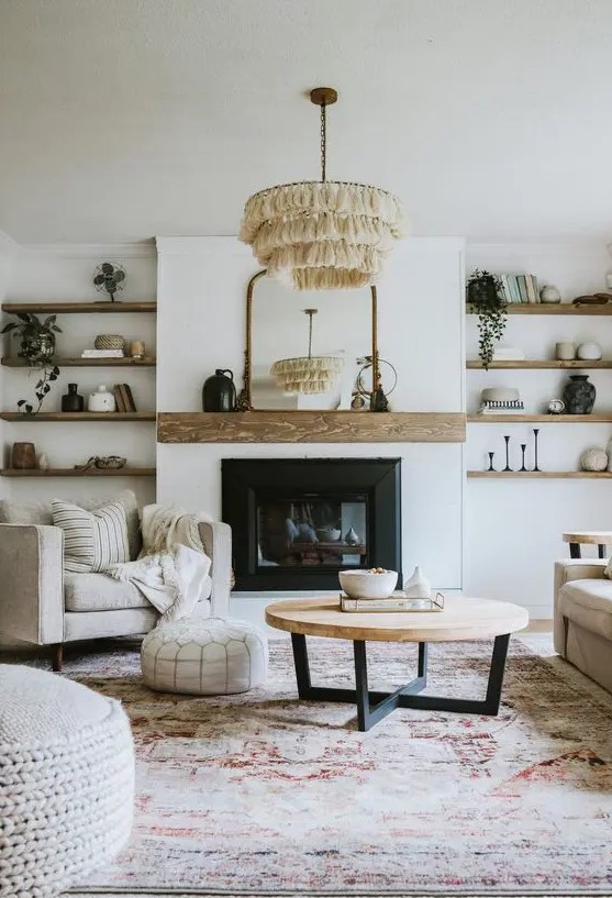 an elegant modern farmhouse living room with a built-in fireplace, built-in wooden shelves, chic neutral furniture, a tassel chandelier