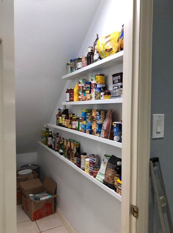 https://www.digsdigs.com/photos/2023/09/a-staircase-pantry-with-open-shelves-boxes-and-additional-lights-is-a-smart-and-easy-solution-to-store-food.jpg