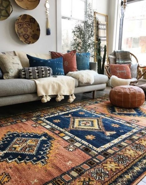 a gorgeous boho living room with boho rugs, pillows, faux fur and leather, decorative baskets and potted greenery