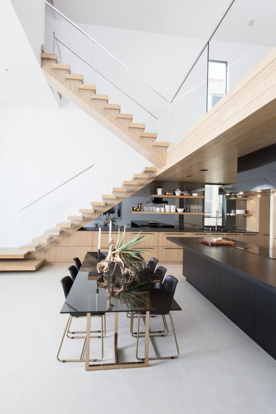 a large stained kitchen built in udner the staircase, with a mirror backsplash and open shelves, a black kitchen island