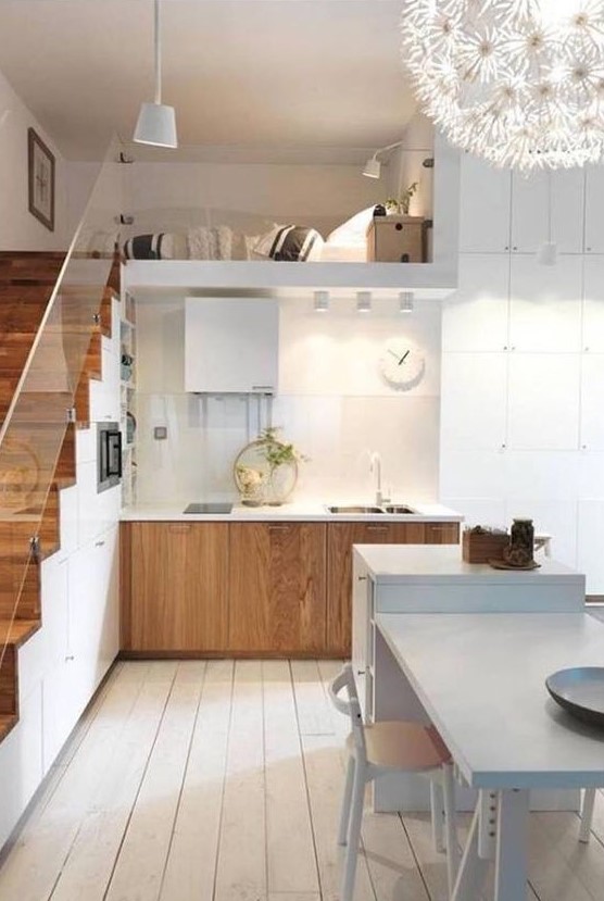 a stylish Nordic kitchen with stained lower cabinets, a staircase that hisde a lot of storage space, a white kitchen island with a table