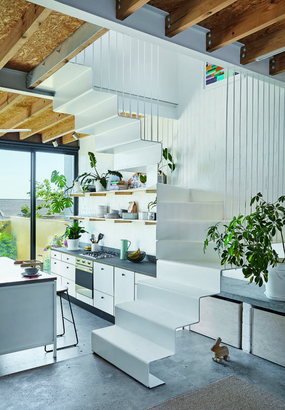 an under the stairs kitchen with open shelves and cabinets and potted greenery is a stylish way to save a lot of space