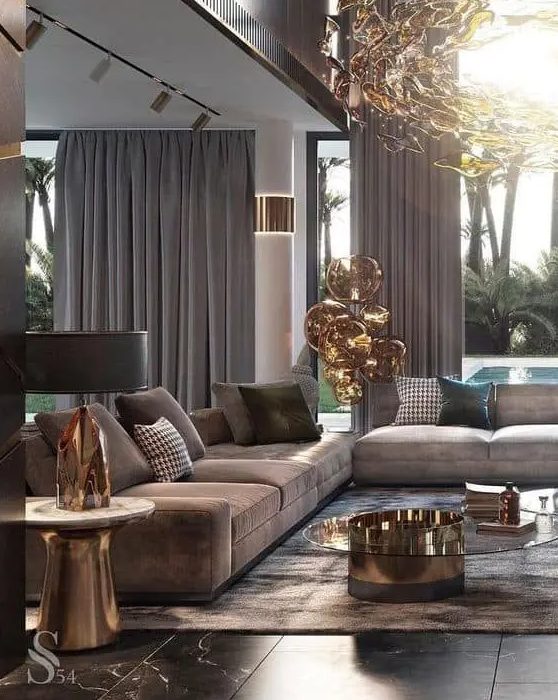 26 An Exquisite Taupe Living Room With Taupe Sofas And Curtains A Brown Rug A Glass And Metal Coffee Table And A Gorgeous Chandelier 