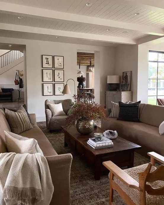 5 Living Room Decor Trends For 2024 And 45 Ideas DigsDigs   06 A Welcoming Modern Earthy Living Room With Greige Seating Furniture A Low Dark Stained Coffee Table A Grid Gallery Wall And A Potted Plant 