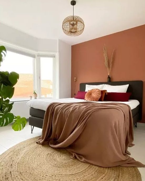 4 Bedroom Trends For 2024 And 40 Examples DigsDigs   07 A Lovely Bedroom With A Boho Feel A Terracotta Accent Wall A Black Bed Bold Bedding A Wooden Pendant Lamp And Some Plants 