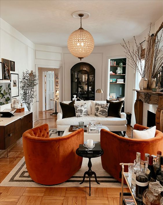 38 A Bold Living Room With A Fireplace And A Wooden Mantel A White Sofa Orange Chairs Built In Shelves A Credenza And A Statement Phere Lamp 