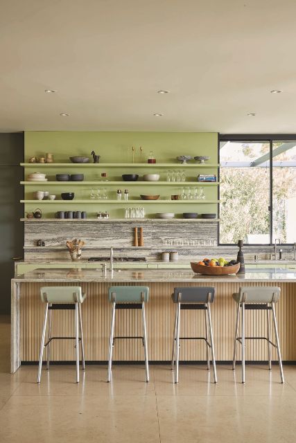 A Modern Kitchen With A Chartreuse Wall With Shelves A Stone Backsplash And Countertops A Fluted Kitchen Island 