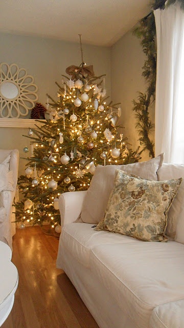 شجرة عيد الميلاد مزينة بزخارف بيضاء وذهبية وأضواء وثلج ثلج وزخارف كرة ثلجية مدهشة