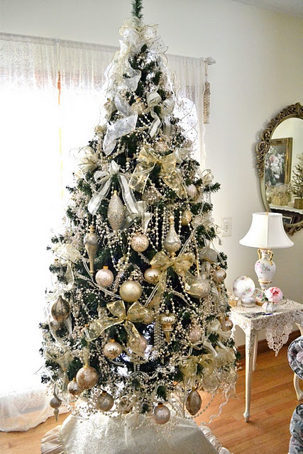 شجرة عيد الميلاد اللامعة المزينة بزخارف ذهبية بأشكال مختلفة ، وأقواس بيضاء ، وأكاليل مطرز باللؤلؤ هي فكرة جميلة
