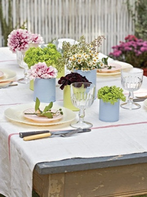 طاولة زنبركية باستيل مع علب من الصفيح الباستيل بدلاً من المزهريات وأزهار الربيع وألواح الباستيل وأجهزة الشحن