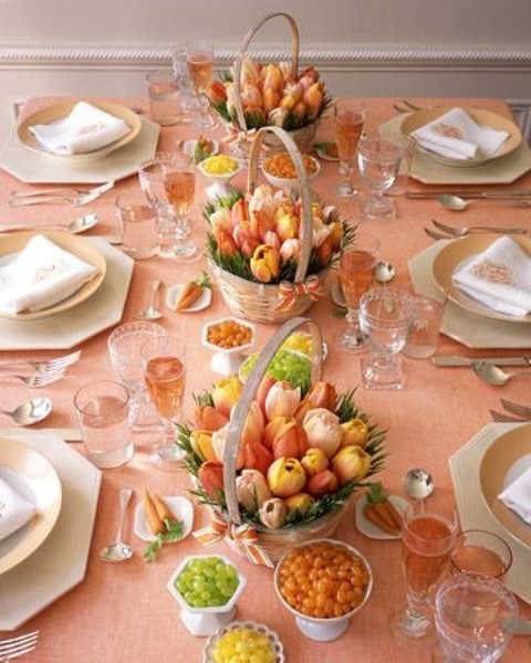 طاولة زنبركية ملونة مع مفرش طاولة وردي خوخي ، قطع وسط زنبق زاهية في سلال ، ولمسات مذهبة