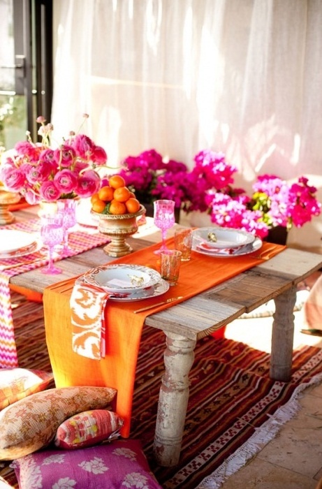 إعداد طاولة فائق السطوع وملون على الطراز المغربي ، مع أزهار وردية ومناديل وعداء ووسائد مشرقة