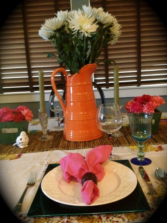 طاولة زنبركية ملونة مع إبريق برتقالي لامع ومناديل زهرية وأزهار