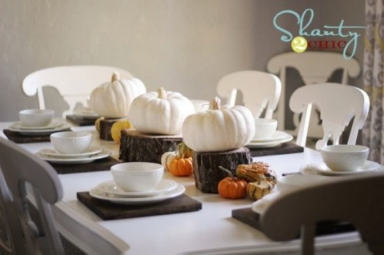 a modern rustic Thanksgiving table with brown placemats, white porcelain, white pumpkins on tree stumps